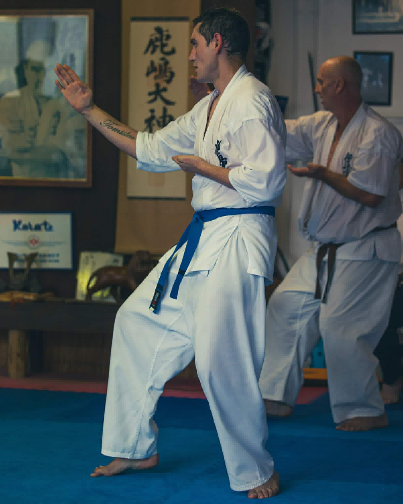 Karate student practicing hand technique with an instructor behind him